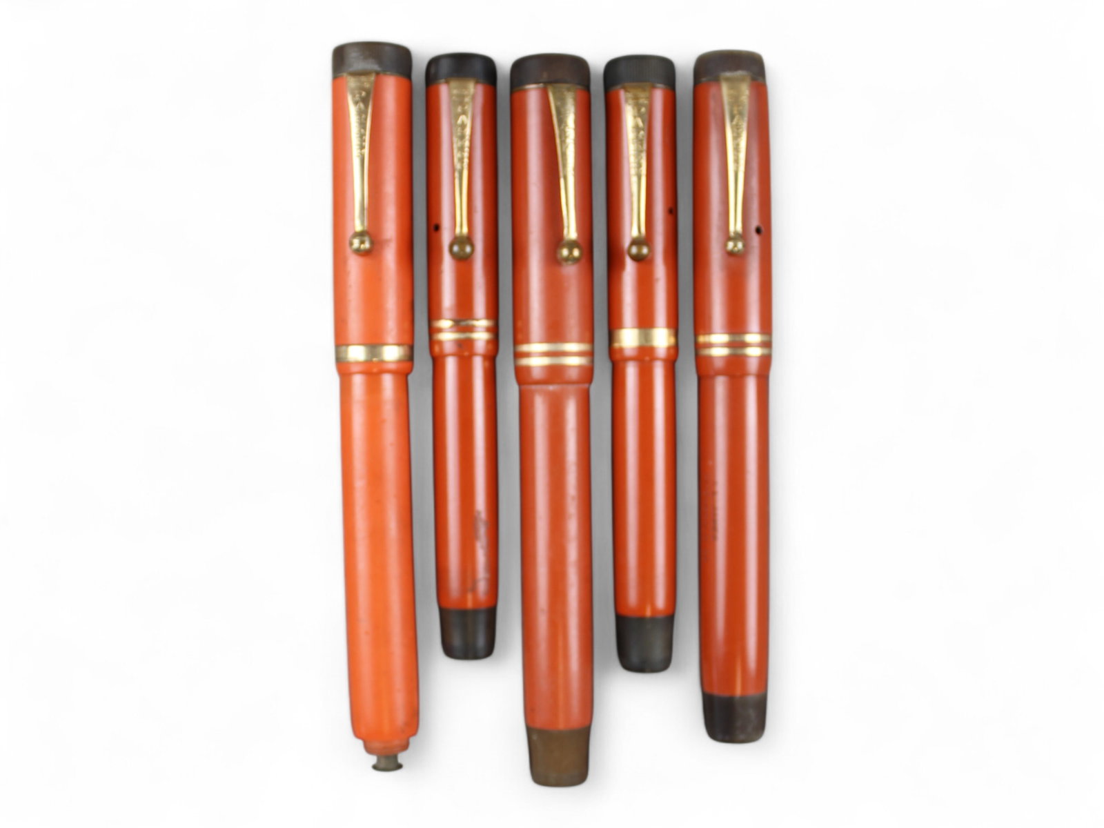 Parker Duofold Red Hard Rubber & Permanite Group: (2) Parker Duofold Permanite senior fountain pens, (1) red hard rubber senior fountain pen (cracked barrel near section), and (2) permanite junior fountain pens. Unrestored.