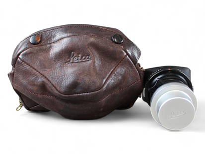 Leica Elmarit 2.8 28mm Lens: Leica Elmarit 2.8/28mm lens, serial number 2062025 with lens hood 12501M. Very minor wear. In brown leather Leica case.