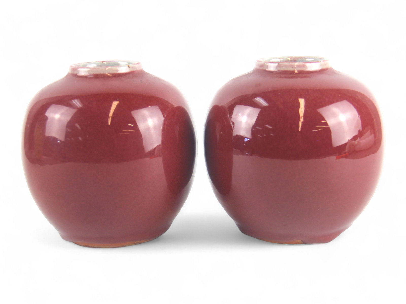 Pair of Chinese Sang de Boeuf Bowls / Vases: Pair of Chinese Sang de Boeuf (oxblood) glazed vases, each with rich, even red glaze shading slightly at the rims and pooling at the bases. Both measure approx. 5" high. Bases with unglazed foot rings