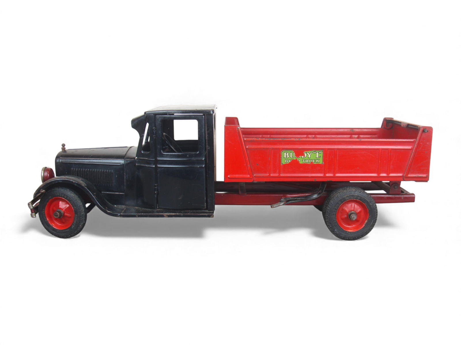 Buddy L #2001 Junior Line Dump Truck: Circa 1930's Buddy L Junior Line pressed steel dump truck featuring an enclosed cab with visor, opening and closing doors, wheels with six embossed simulated spokes, and period Firestone rubber tires.