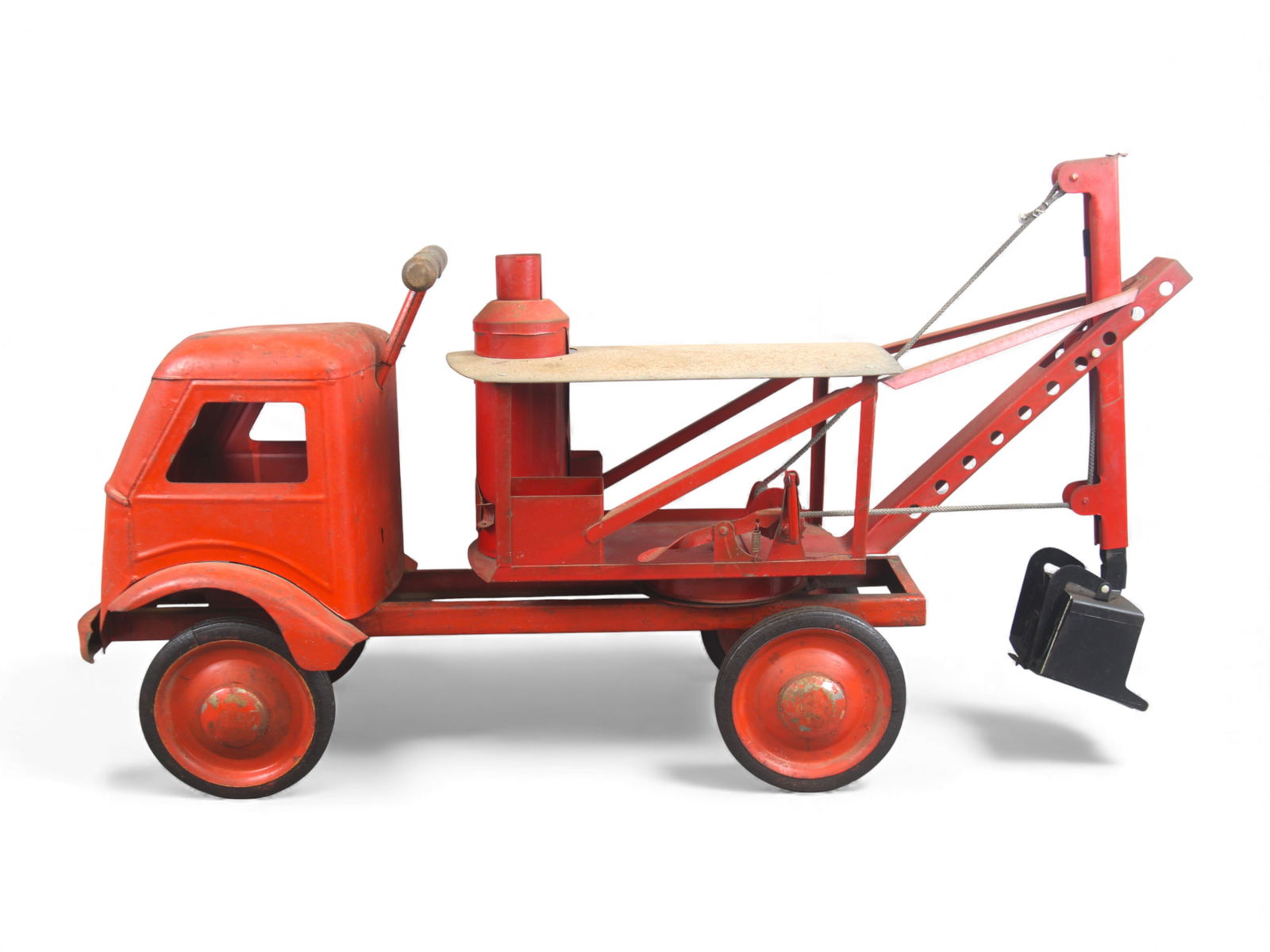 Early Pressed Steel Ride On Shovel Truck: Early unmarked pressed steel ride-on shovel truck, likely 1930/40's, featuring a solid steel cab, saddle-style seat, and manually operated shovel boom with pulley and cable mechanism. Constructed in h