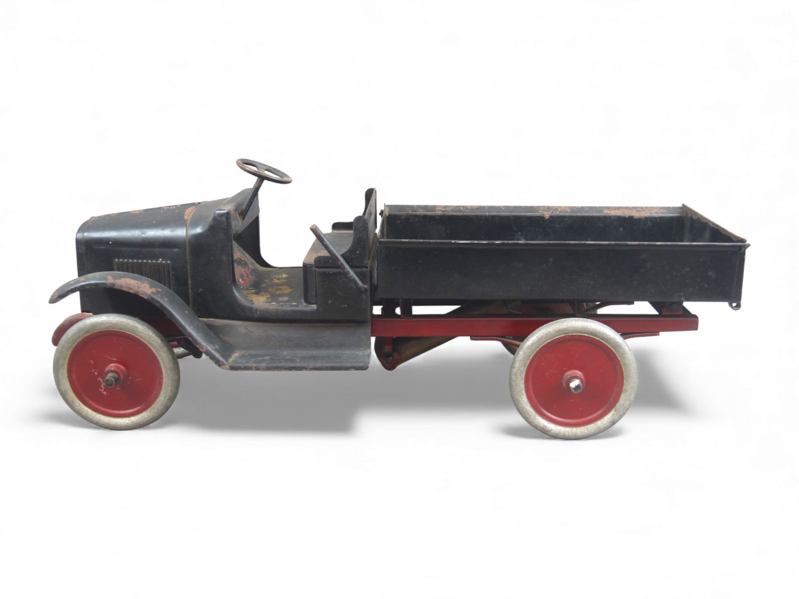 Buddy L Hydraulic Dump Truck: Early Buddy L pressed steel hydraulic dump truck with open black cab, red chassis, fold down lift gate, and red steel disc wheels. Features the original Buddy L decal on the seat panel, and decal on t