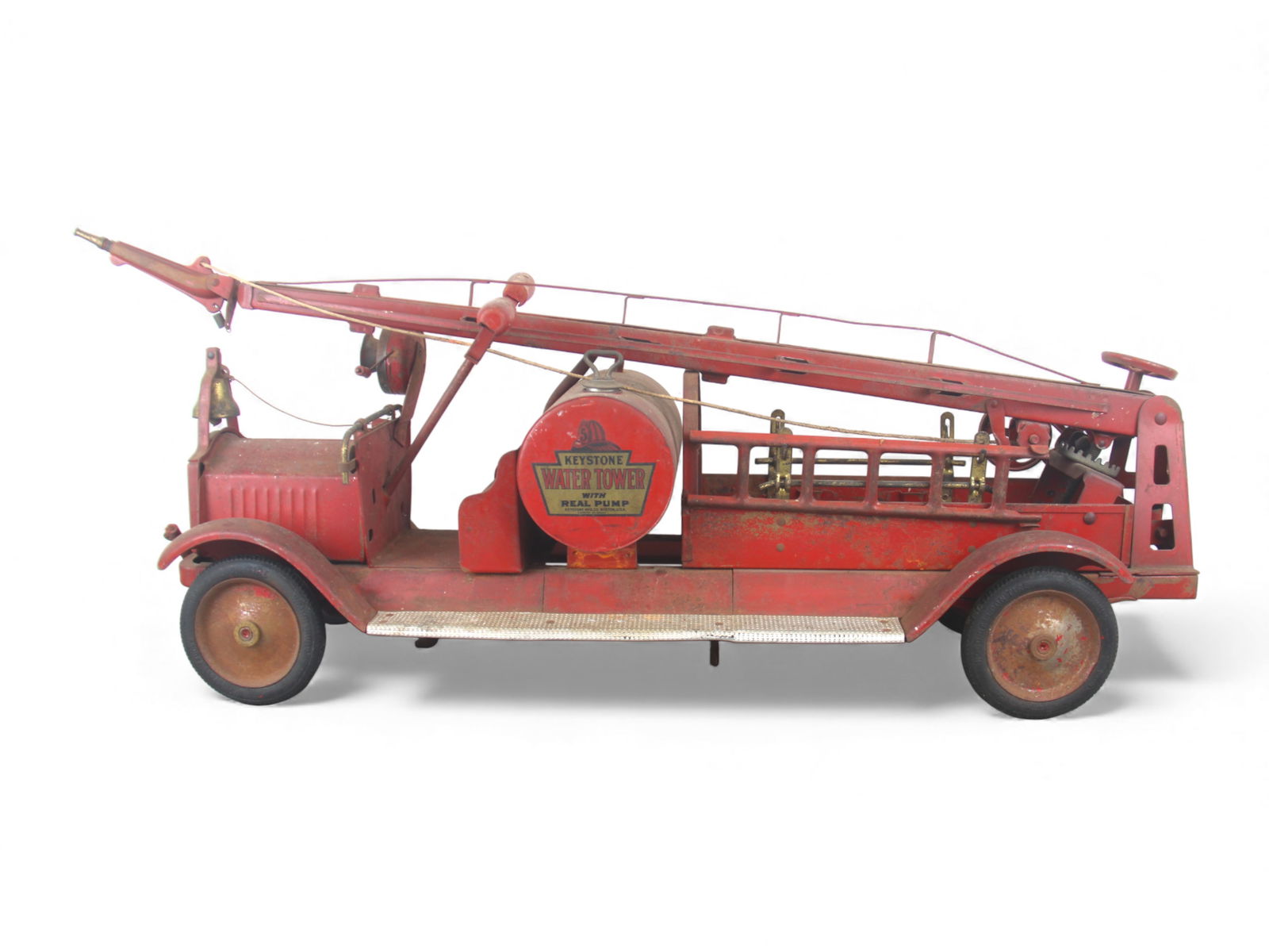 Early Keystone Ride-On Water Tower: Painted pressed steel with rubber wrapped steel hubs 31" long. Its fairly complete, missing 1 side ladder, some hose deterioration. Water tank appears intact and whole. Siren sound works, has