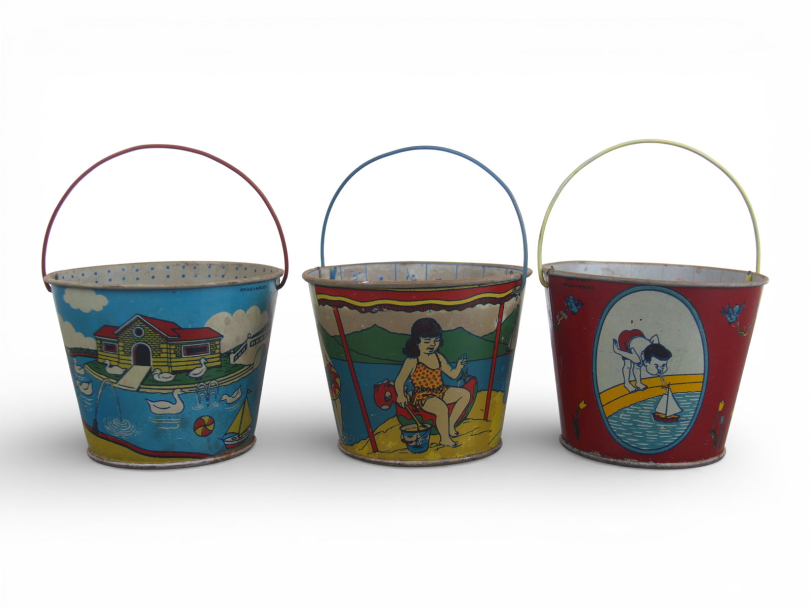 (3) Tin Litho French Children's Sand Pails: Each marked "Imp. Lujo Metalico". Each depicts colorful playful graphics throughout. Approx. 3-1/4" tall. Each shows surface wear with scuffs and scratches. Shipping: Weiss Auctions offers