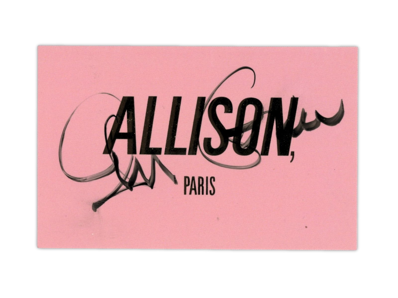 Elvis Costello Signed Business Card: Pink business card from the Paris women's clothing store Allison, signed in black marker by Elvis Costello. The signed card makes a direct reference to Costello's song "Alison." Uncommon signed