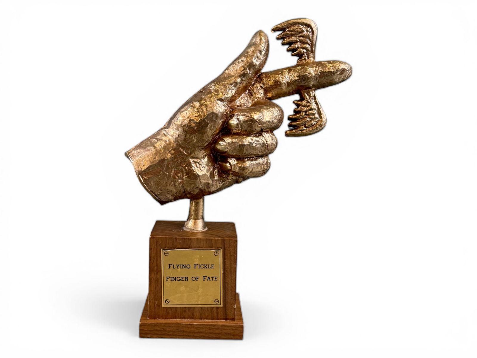 Flying Fickle Finger of Fate Award: Metal award mounted on a wooden base depicting a hand with a winged pointing finger above a metal plaque reading "Flying Fickle Finger of Fate." The underside is stamped "George Schlatter - Ed