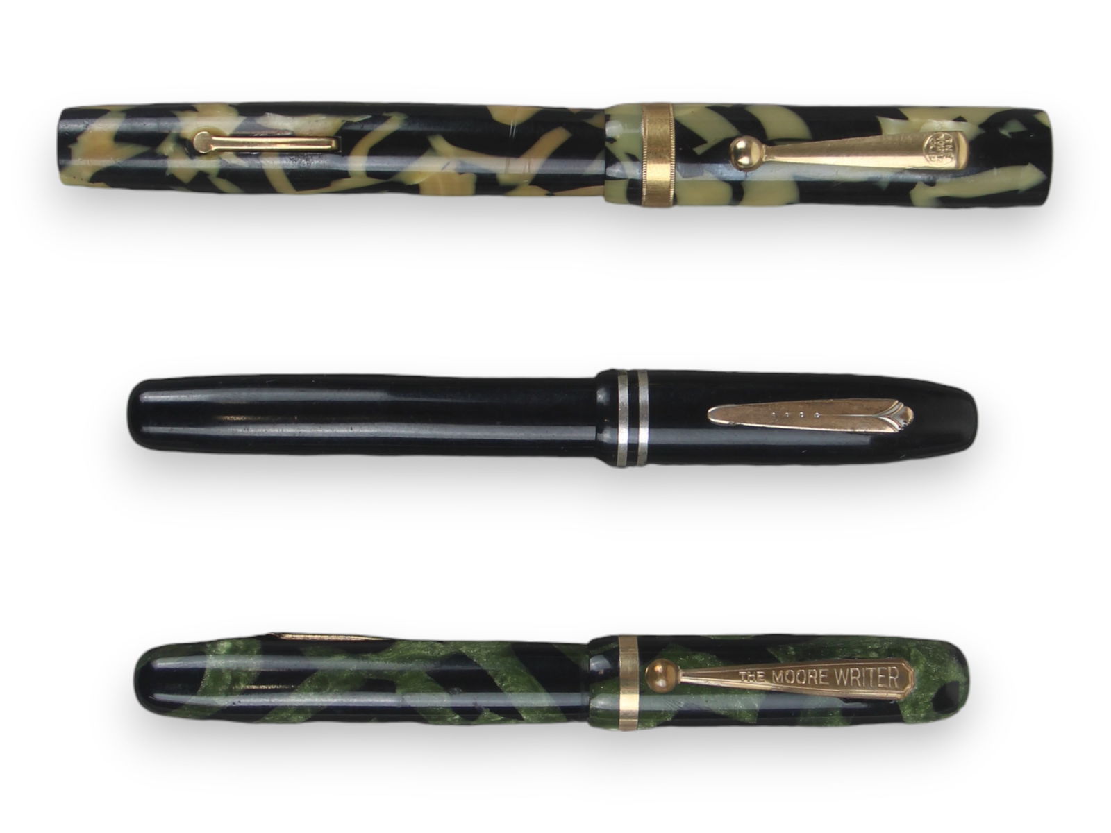 (3) Moore Celluloid Fountain Pens: 3 Moore celluloid fountain pens including Model 95 in black and pearl, Moore Writer in marine green, and Junior in black celluloid. Minor wear. 14k gold nibs; 2 are flexible. Not restored.Shipping: