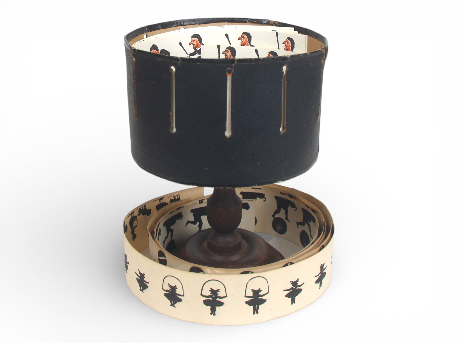 Wheel of Life Zoetrope Viewer: Paris, Wheel of Life Zoetrope Viewer. Cardboard slotted cylinder with 5 double sided black and white action strips. Label affixed to bottom of cylinder marked "Aux Galleries Lafayette Paris". Wooden