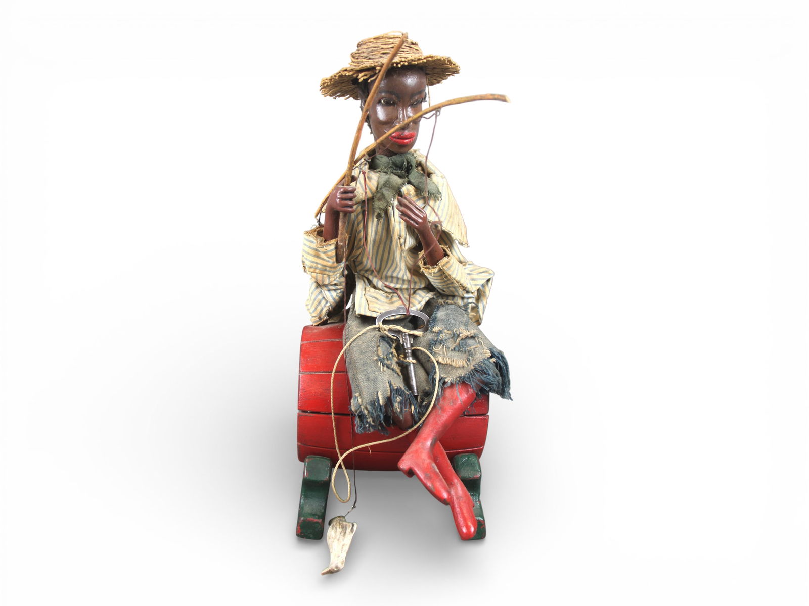 Folk Art Automaton, Fisherman on Barrel: Hand-carved and polychrome wooden folk art automaton depicting a fisherman seated atop a barrel-form base. The figure features carved head and hands, applied fabric clothing, and a woven straw hat,