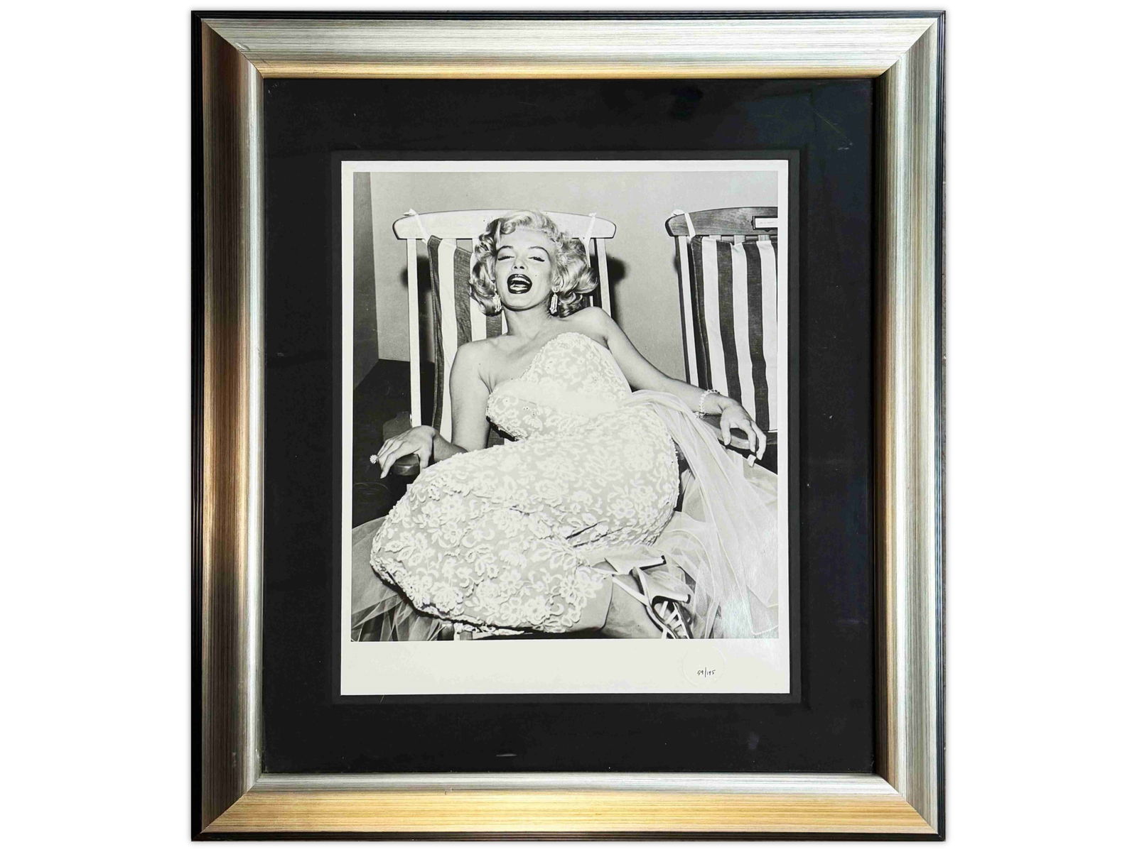 Marilyn Monroe Ltd Ed Photo by Frank Worth: Limited edition silver gelatin photograph of Marilyn Monroe seated on a deck chair in a floral pattern dress. Blind stamped at the lower right by the Estate of Photographer Frank Worth. Hand numbered