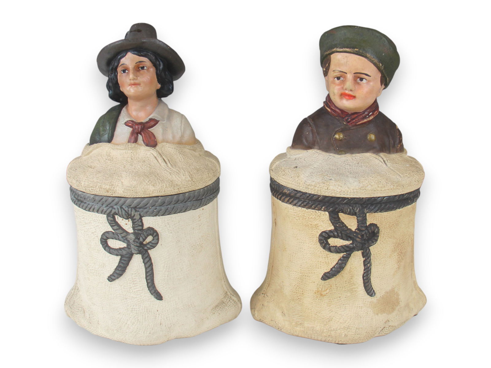 Lot of Two Terra Cotta Tobacco Jars: Each 8 1/2" Tall showing Children coming out of tobacco bales. See images for details.Shipping: Weiss Auctions offers full-service, in-house shipping for nearly all items in this auction. For a
