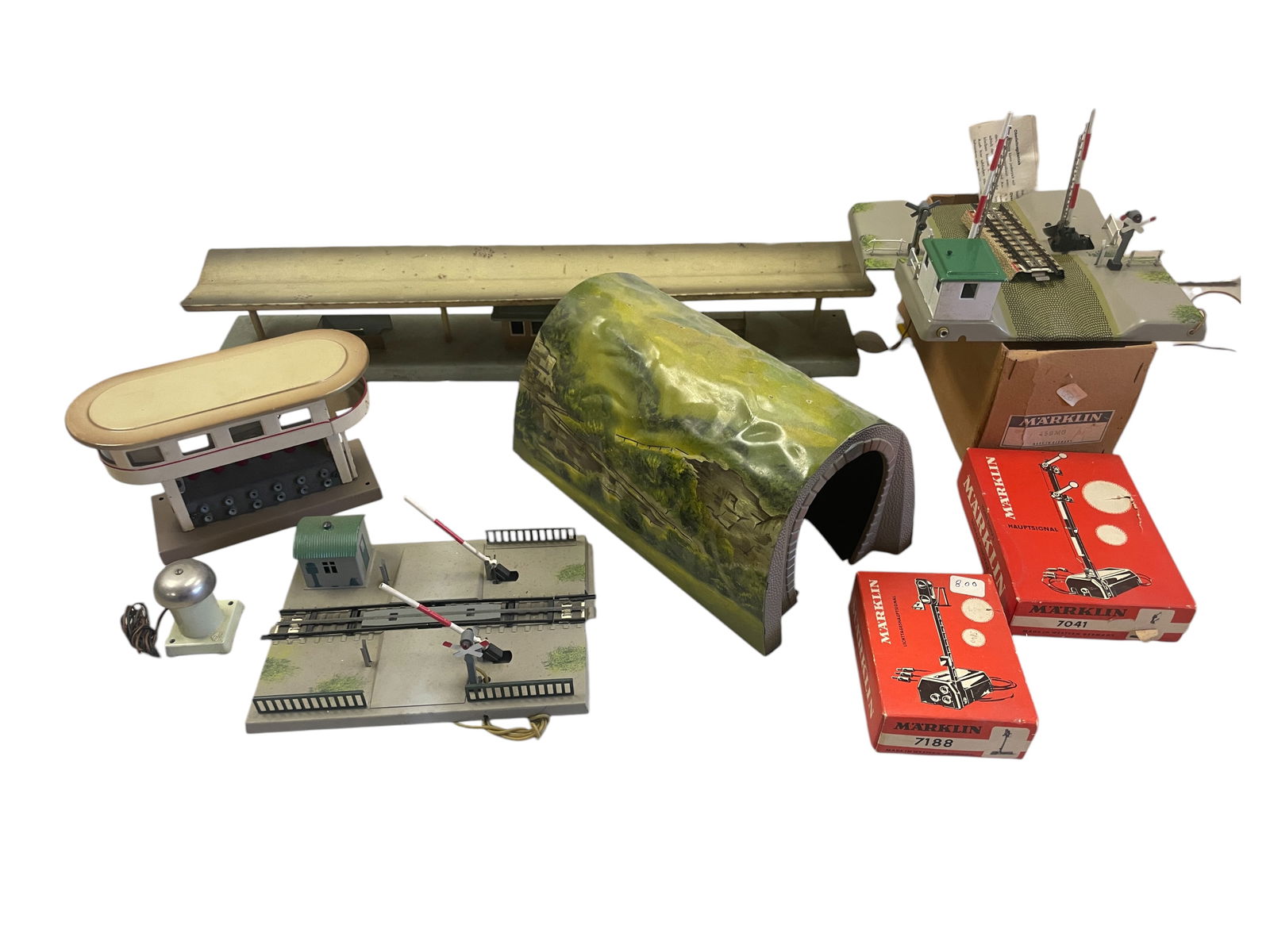 9 Vintage Marklin HO Accessories: HO Gauge. Includes a 423 Station platform, dirty; 452 Tunnel; 438 Station Bell; 459MG Hi-Way Electric Grade Crossing with box bottom; 457 Grade Mechanical Crossing; 473/6 Switch Tower; 7188 Block Sign