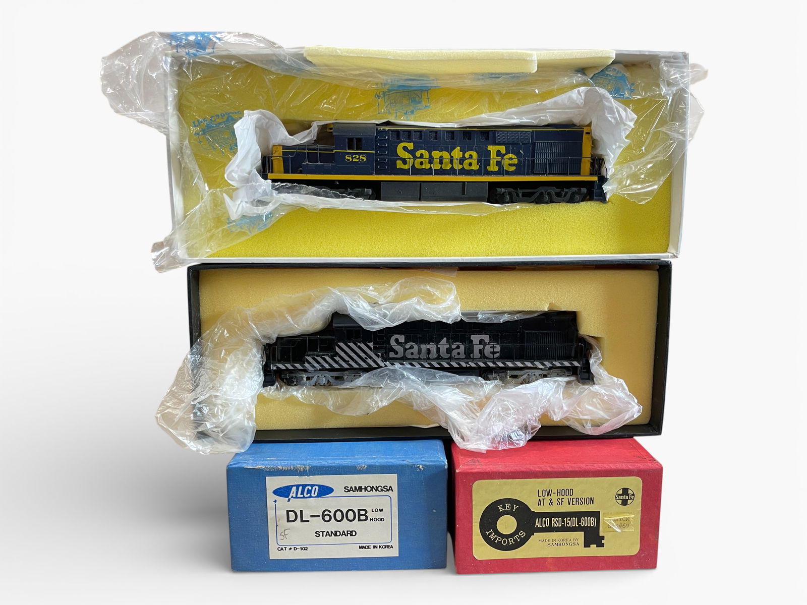 2 Brass HO ATSF DL-600B Low Hood Diesels: HO Gauge. Includes an Alco Custom Painted and decaled, #828, open frame motor; KEY Black/silver version, custom Painted, decaled, un-numbered, open frame motor with paperwork & decal sheet. They shows