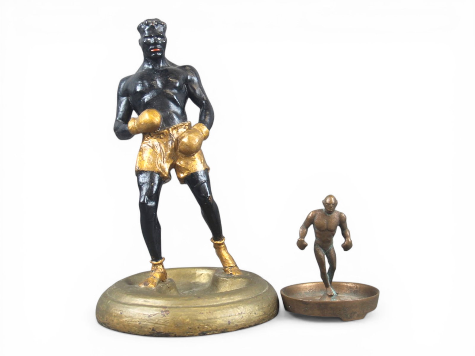 (2) Boxing Statue Figural Ashtrays: Includes 4" bronze figural boxer ashtray, and plaster statue ashtray approx. 10", marked T.C. Ewell and dated 1923. Both show wear with surface scuffs. The plaster statue has a few areas of paint loss