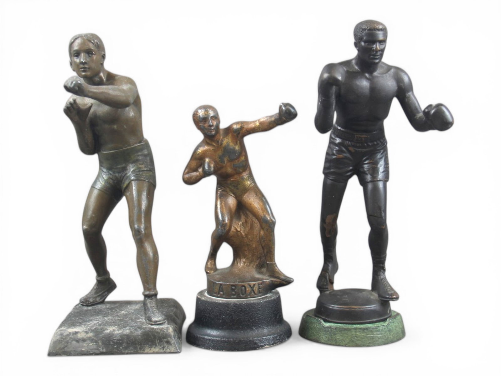 (3) Boxing Statues: Includes 8" metal statue marked "La Boxe", 10" metal statue, and 10" composition statue (has cracks and chips). All show surface wear with scuffs and scratches throughout. Shipping: Weiss Auctions