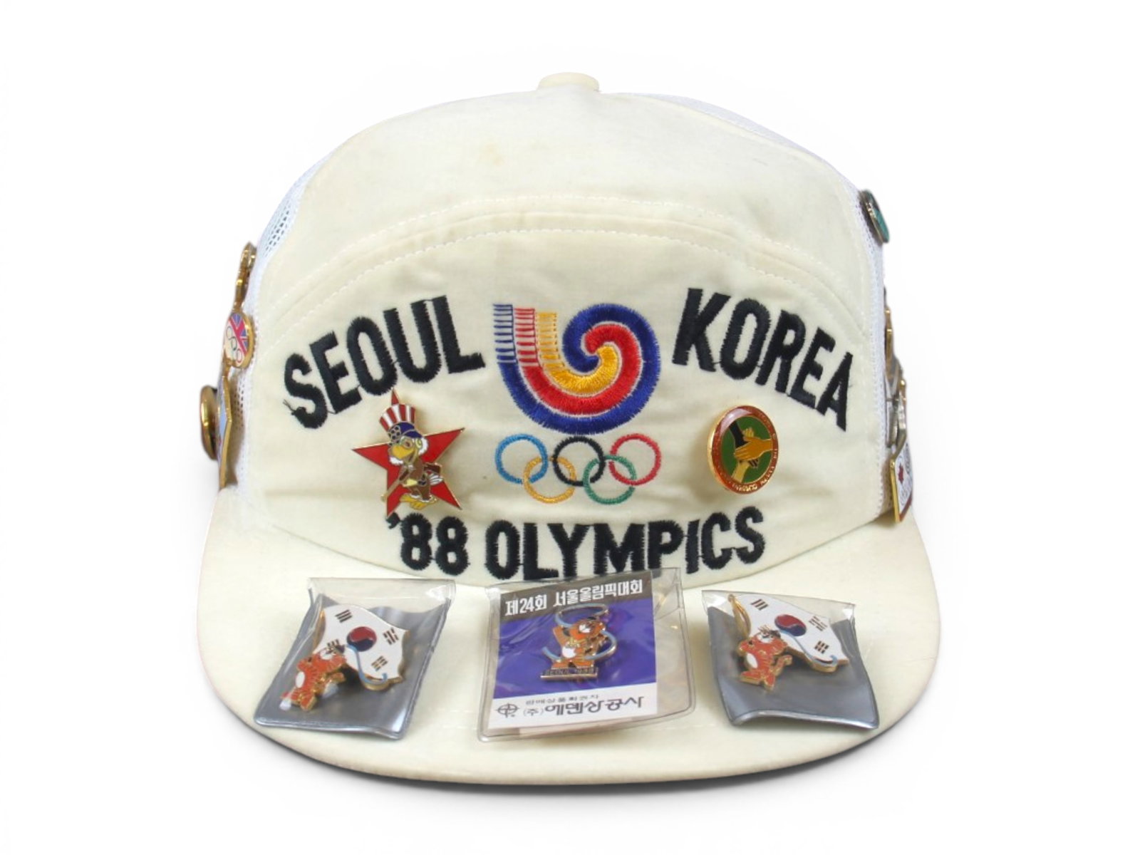 1988 Seoul Korea Olympic Hat & Pinbacks: Offered is a Vintage 1988 Seoul Korea Olympics hat, along with a grouping of approx. 40 pins/pinbacks. Hat has a few light stains. Shipping: Weiss Auctions offers full-service, in-house shipping for n