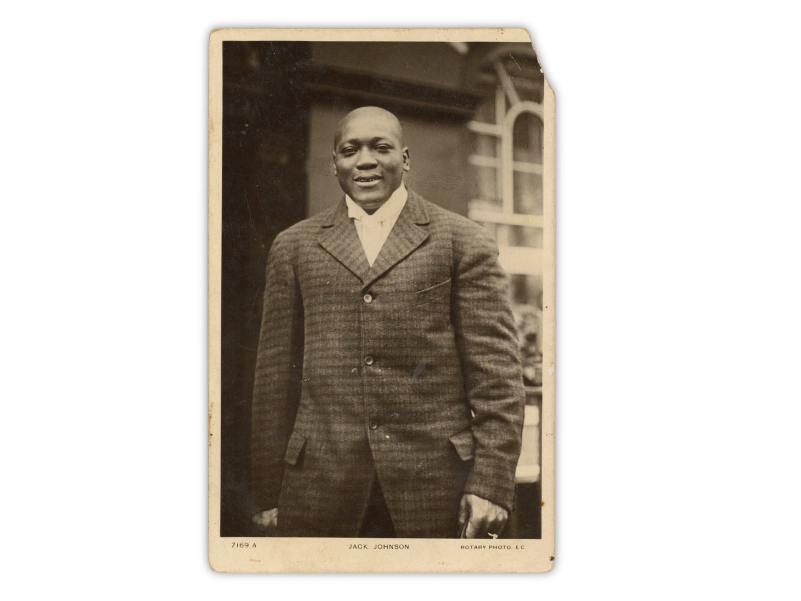 Jack Johnson Real Photo Postcard: Real photo postcard of Jack Johnson in a suit, issued by Rotary Photographic Series, printed in Britain. Johnson was the first Black Heavyweight Champion (1908-1915), whose reign marked a major and co