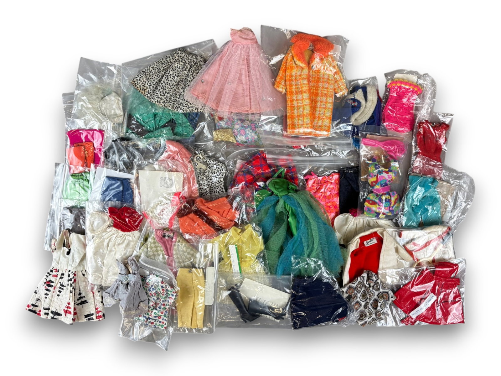 Vintage Barbie Clothes Assortment: Box lot of Barbie, Ken, and Skipper clothing, some tagged. Circa 1960s-1970s. Shipping: Weiss Auctions offers full-service, in-house shipping for nearly all items in this auction. For a shipping quote