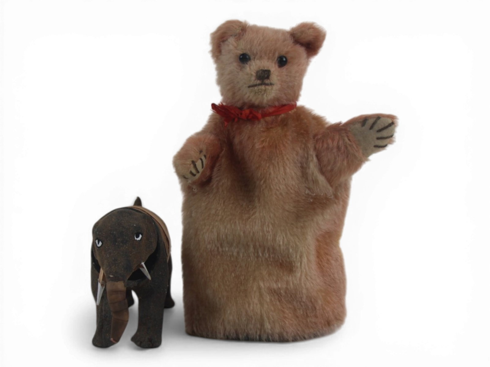 (2) Steiff Puppet and Elephant Nodder: 9 inch rose mohair Steiff bear hand puppet with glass eyes and a papier mache nodding elephant measuring approximately 4 by 6.5 inches. Circa 1910-1950s. Shipping: Weiss Auctions offers full-service, 