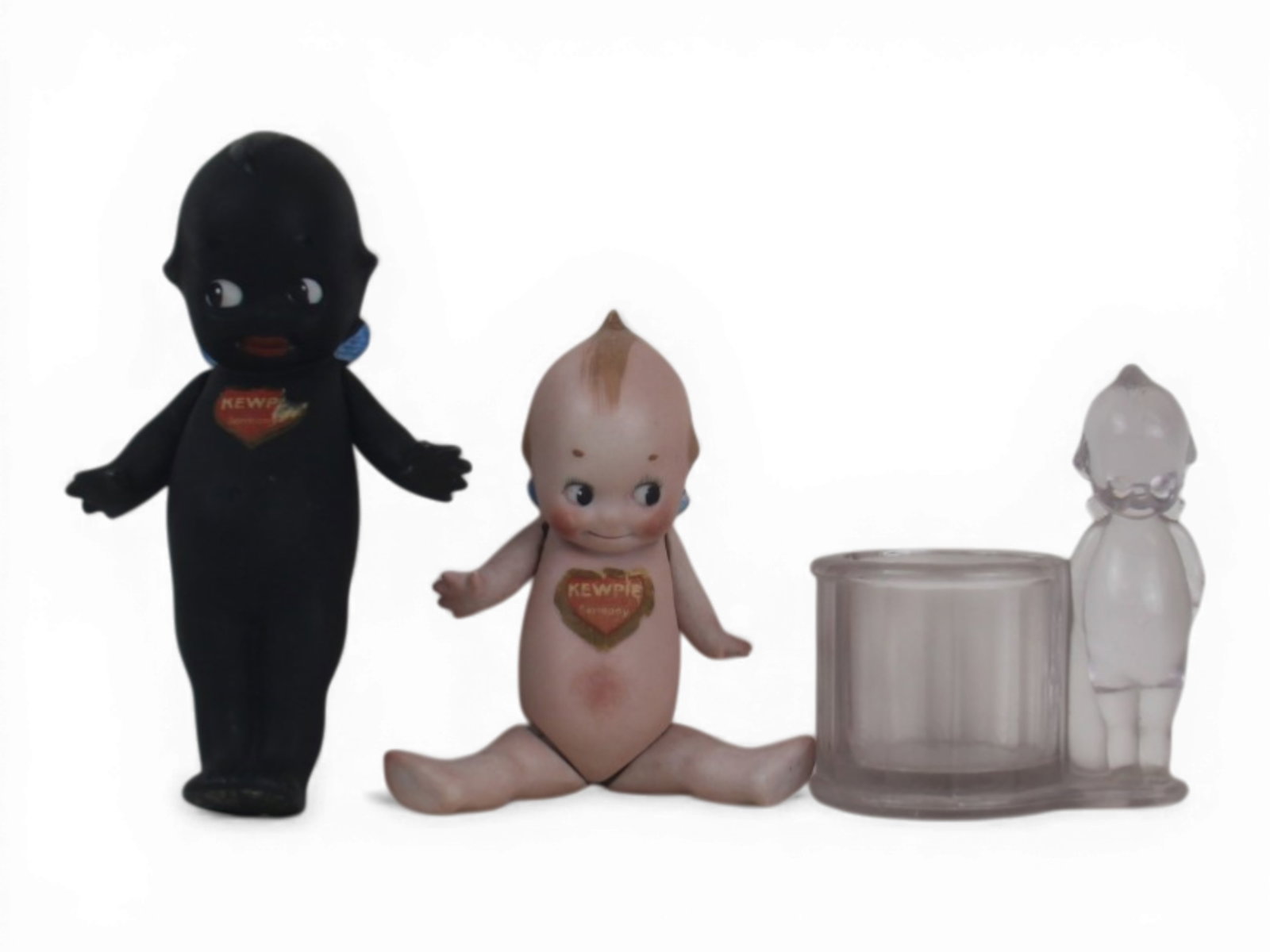 (3) Rose O'Neill Kewpie Collectibles: Group of three Kewpie items including a 6 inch all bisque example with worn label, a smaller bisque Kewpie, and a glass Kewpie toothpick holder marked Kewpie 2862 dated 1913. Shipping: Weiss Auctions