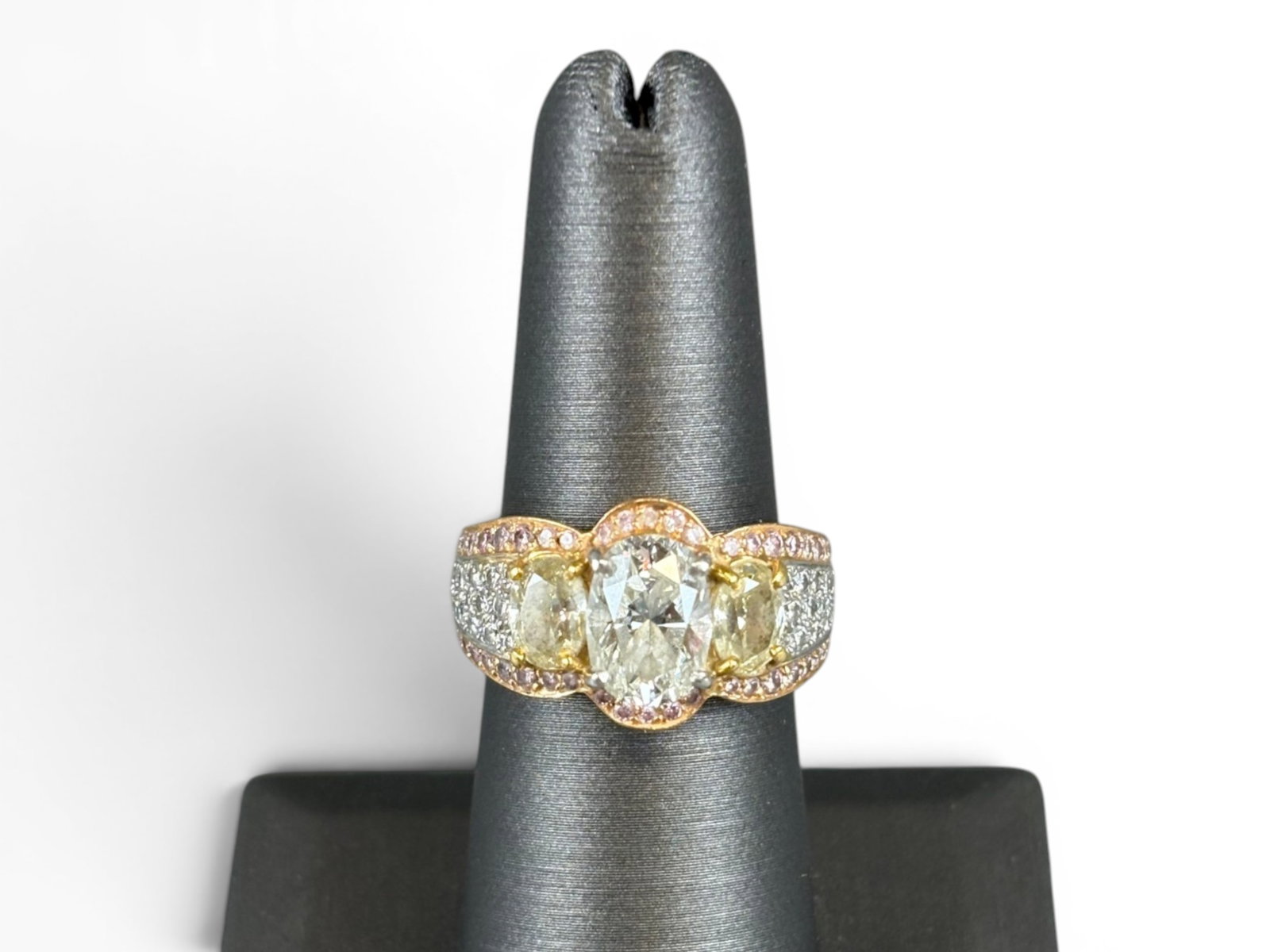 18K Gold Multi-Diamond Ring: 18K yellow gold ring centered by an oval brilliant-cut diamond weighing approximately 1.50 carats, H-I color, slightly included 2 clarity. Accented by two oval-cut side diamonds weighing