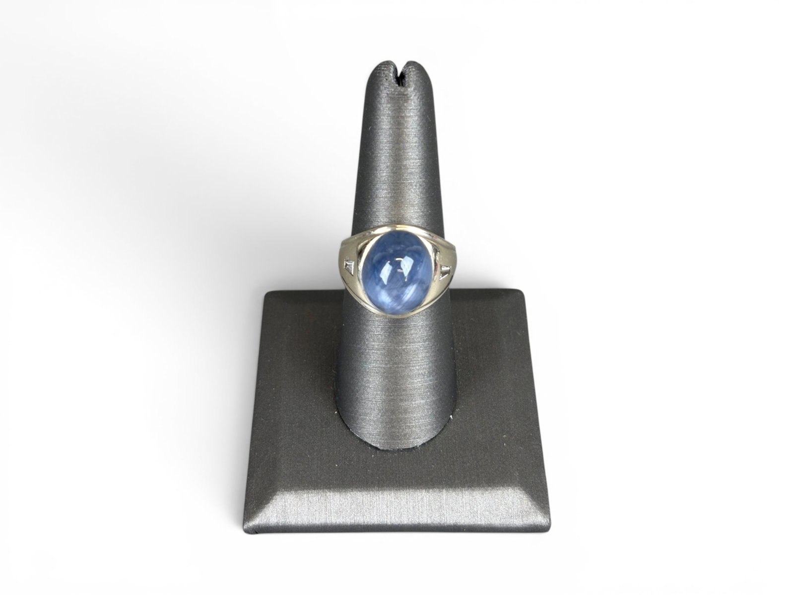 14K Gold Star Sapphire Ring: 14K white gold ring set with a natural blue star sapphire cabochon measuring approximately 14.53 x 11.90 x 11.56 millimeters, estimated weight 20.50 carats. Further set with two baguette-cut diamonds 