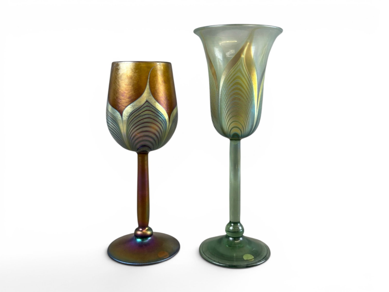 (2) Correia Studio Art Glass Goblets: Pair of Correia studio art glass goblets featuring iridescent finishes with stylized feather and pulled line decoration. One example displays warm gold, purple, and bronze tones with a rounded cup for