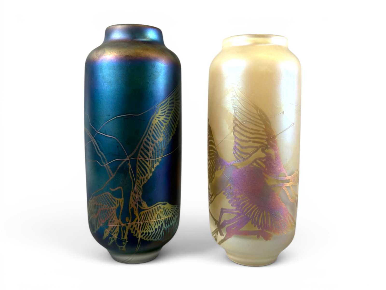 (2) VanderLaan & Bliss Art Glass Vases: Pair of VanderLaan & Bliss studio art glass vases featuring satin iridescent finishes with finely etched crane and marsh bird decoration. One vase displays a pale cream ground with bird motif in soft