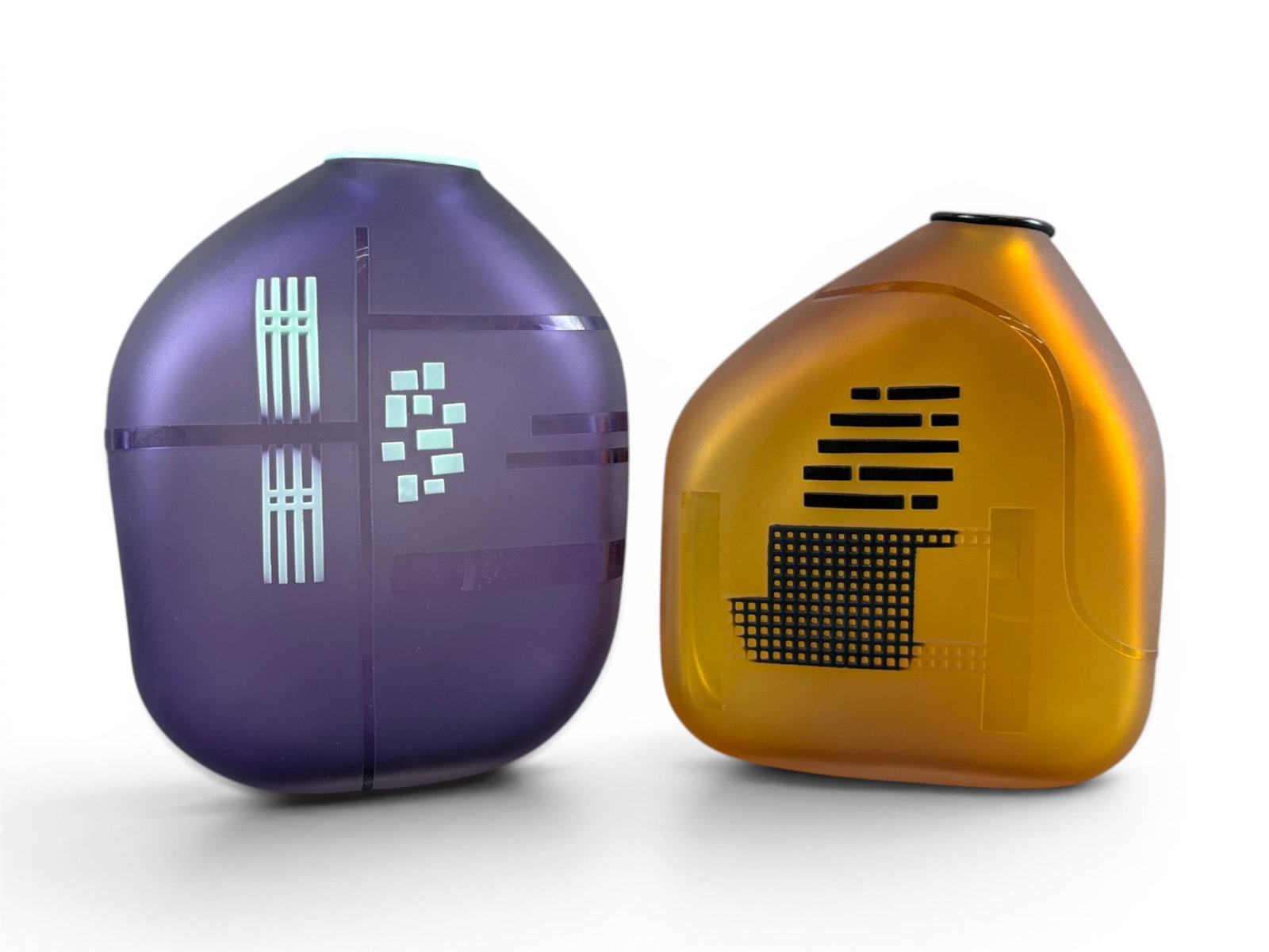 (2) Jim & Connie Grant Studio Art Glass Vases: Pair of Jim and Connie Grant studio art glass vases from the 1980's, each featuring frosted surfaces with geometric Art Deco-inspired decoration. One vase displays warm amber coloration with black