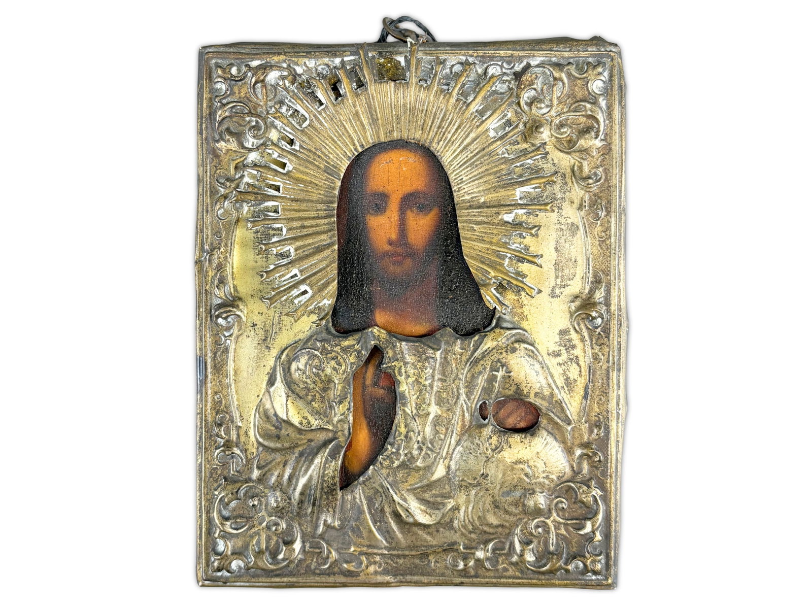 Russian Gilt Brass Oklad Icon: Antique religious icon depicting Jesus, housed beneath a pierced metal oklad-style cover with radiating halo decoration and ornate corner scrollwork. The painted image is visible through cutout openin
