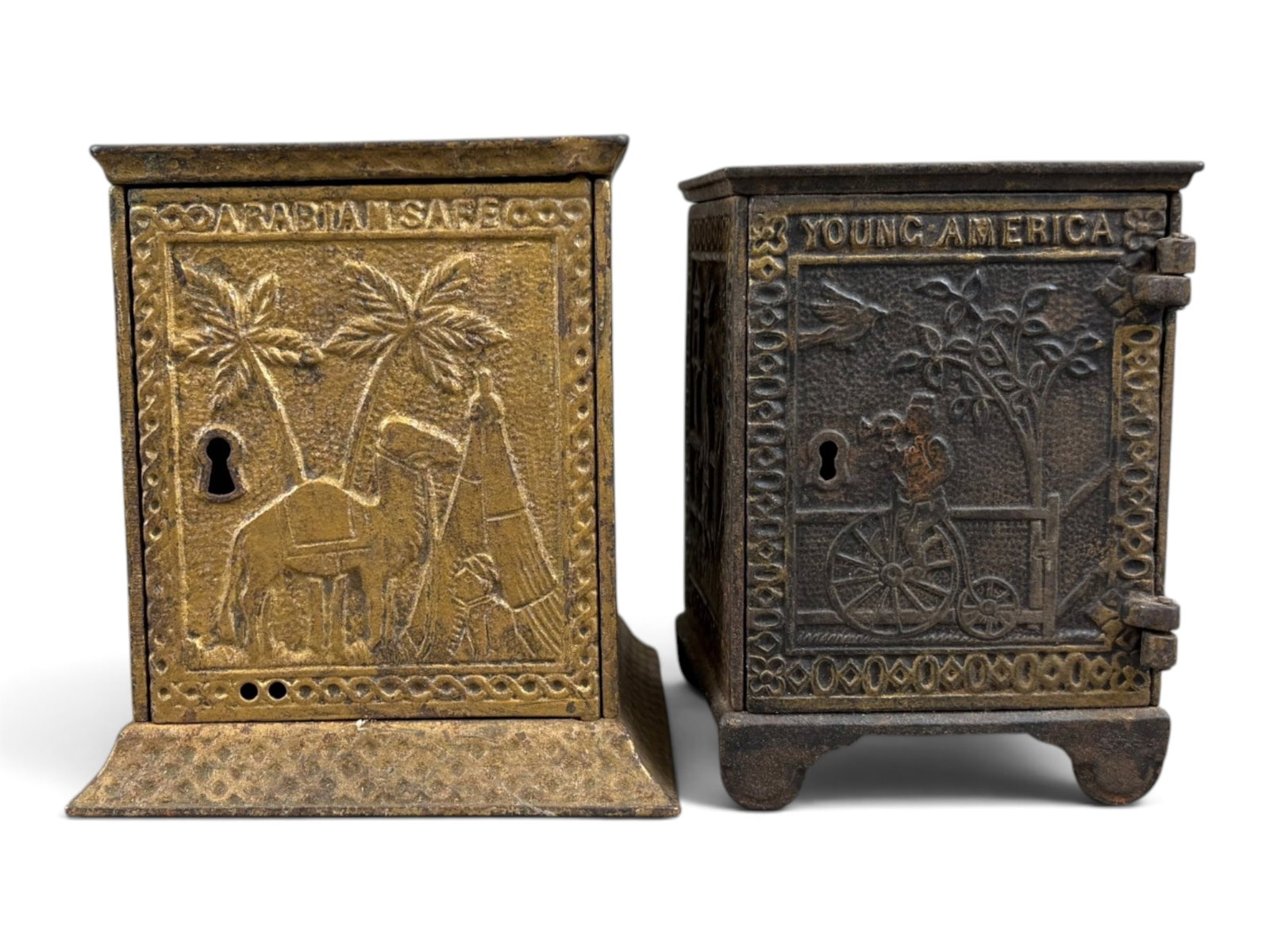 (2) Cast Iron Still Banks: Lot of two cast iron still banks. Includes a Young America bank measuring approximately 4? inches tall and an Arabian Safe Company bank measuring approximately 4? inches tall. Both are in very fine