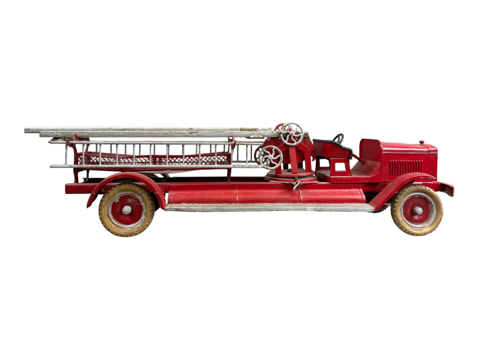 Kingsbury Pressed Steel Aerial Ladder Fire Truck: Circa 1929, Kingsbury Toys large pressed steel aerial ladder fire truck. Impressive early American toy measuring approx. 34.5" long, finished in red with silver-tone ladders and fittings. Features an