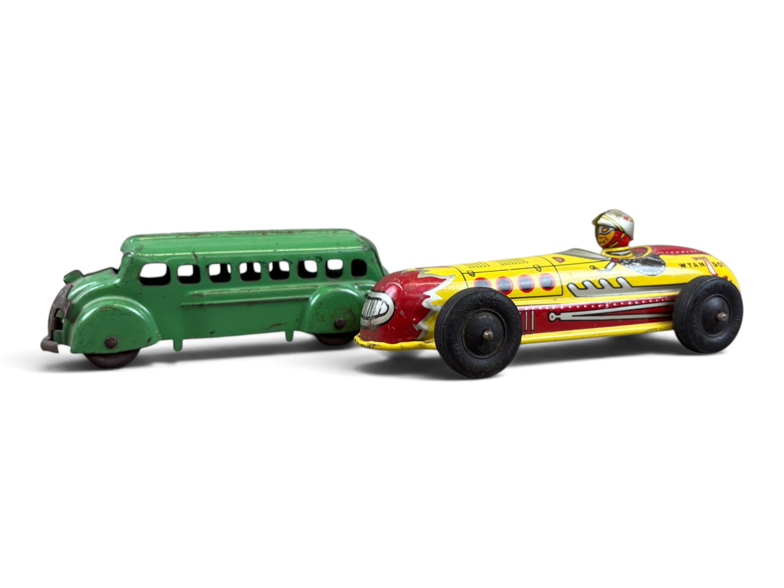 (2) Wyandotte Tin Vehicles: Lot of two vintage Wyandotte tin vehicles. Includes an early 7-inch-long motor bus in green, together with an 8-inch-long tin racing car with driver. Both are in nice condition and make an attractive 
