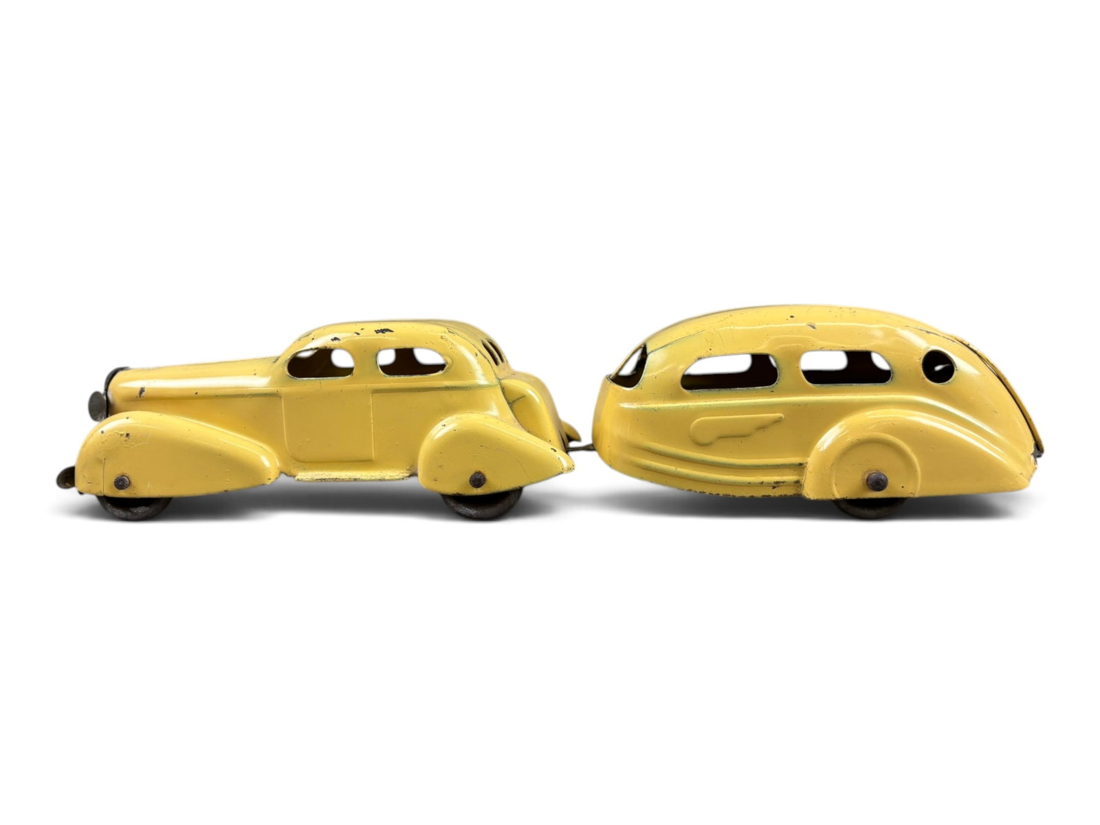 Wyandotte Sedan & Travel Trailer: Wyandotte No. 346 sedan with travel trailer, finished in yellow with black wooden wheels. Measures approximately 11 inches long when coupled together. Overall in very nice condition and an attractive