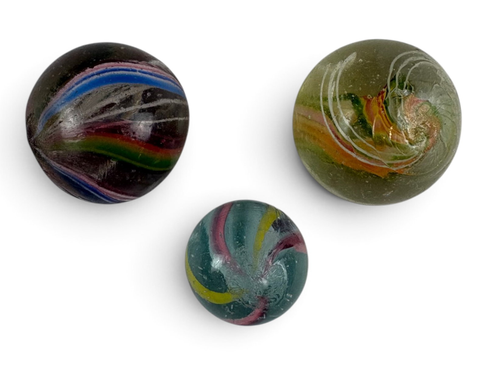 3 Vintage European Hand-Made Marbles: 1920s. Includes a 7/8 inch swirl with green yellow an pink center bands and triple hairline white outer bands; 7/8 inch swirl with 6 white inner bands, alternating red/white/blue outer bands with