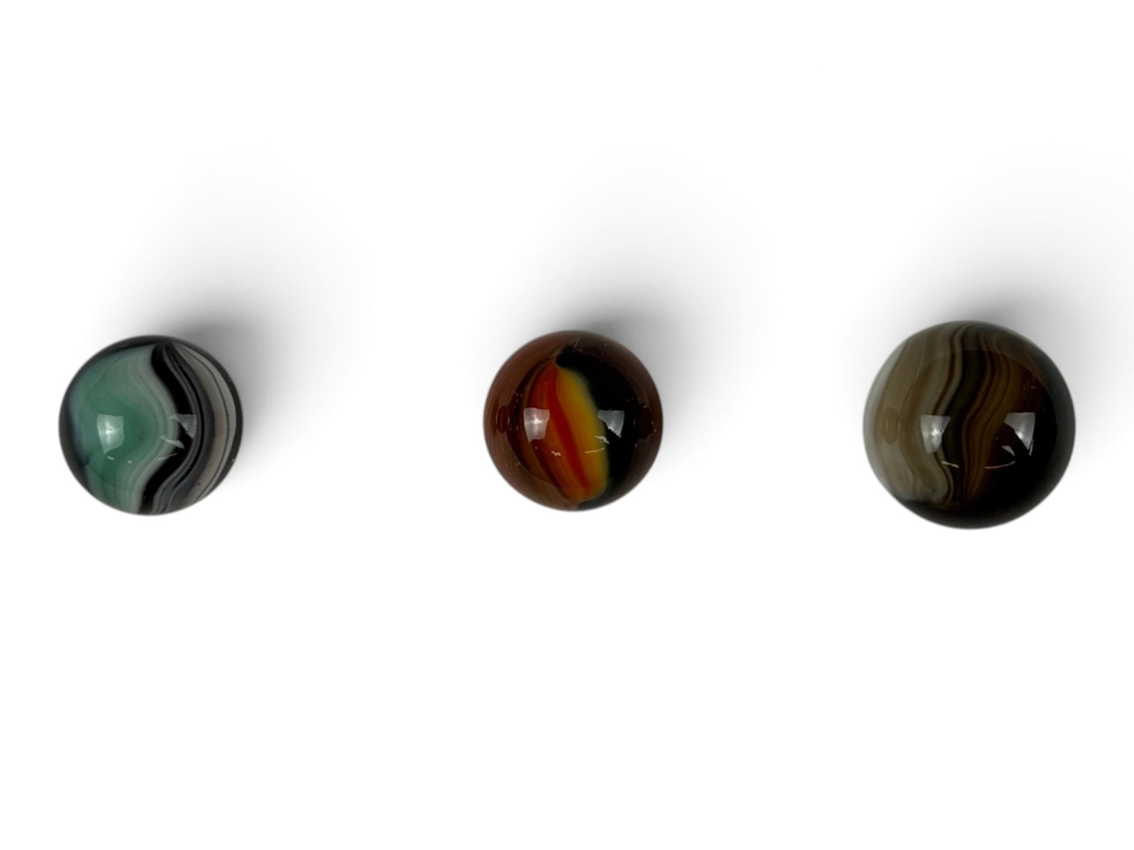 3 Master Marbles, Sunbursts: 1933-1941. Includes an 11/16" Black & Orange is fabulous condition; Unusual 3/4? Turquoise, white & black; And a 3/4+? Brushed Patch. All are clean and shiny, showing light handling Shipping: Weiss