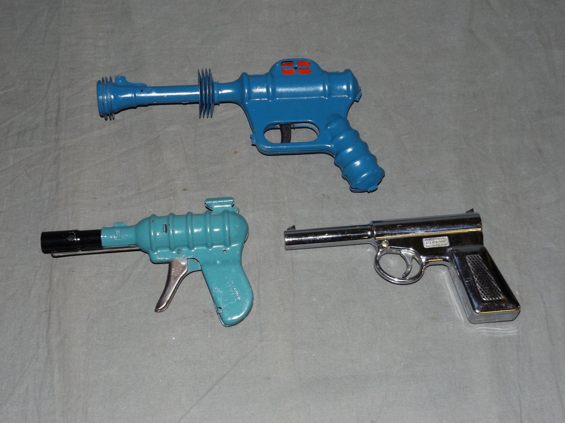 Lot of 3 Toy Space Guns: Includes Daisy Buck Rogers Atomic Pistol (repainted blue, not working), Wyandotte Ray Gun (repainted, working but trigger gets stuck at times), and "Gat" Air Pistol. Each show some wear. Examine