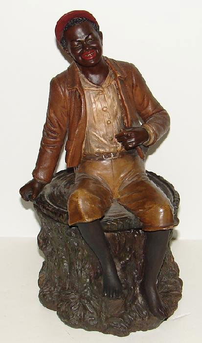 BLACK TOBACCO JAR SITTING ON TREE STOMP: LOT CONSISTS OF A NICE ORIGINAL BLACK AMERICANA TERRA COTTA TOBACCO JAR OF A MAN SITTING ON A TREE STOMP. APPEARS TO BE MARKED "QY BB 8098". APPROX. 11" TALL. HAS LIGHT EDGE AND CORNER WEAR, OVERALL V