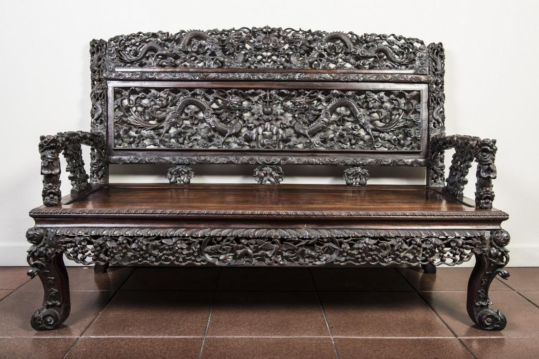 CHINESE CARVED HARDWOOD OR ZITAN SETTEE: The back reticulated with dragons in pursuit of jewels, with dragon fore arms and a rectangular seat with a petal edge, the openwork apron carved with auspicious deer, bird and qilin amid gourds, rais