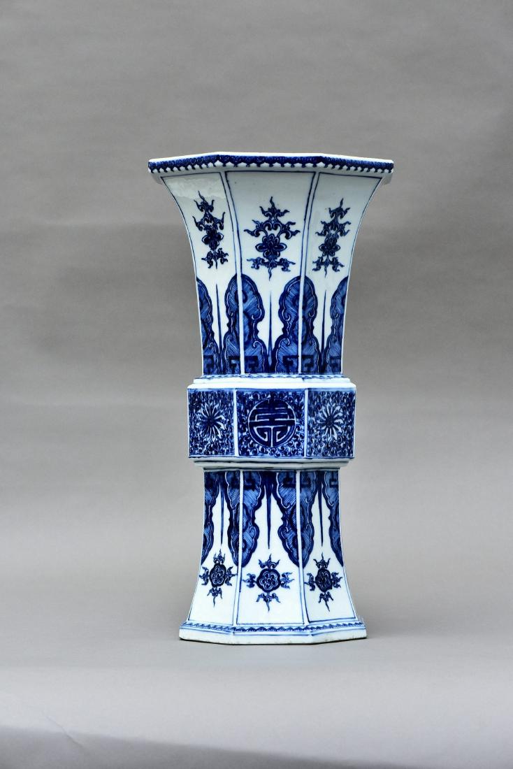 A BLUE AND WHITE PORCELAIN OCTAGONAL BEAKER VASE, QING: A Chinese blue and white octagonal beaker vase of archaistic form with a gently spreading foot and flared rim, decorated with a band of chrysanthemum on the middle-section, the upper and lower section