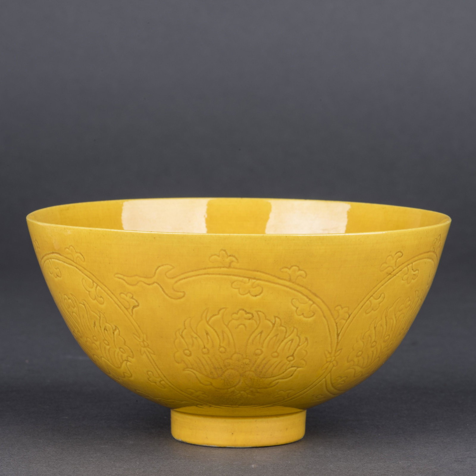 A YELLOW GLAZED BOWL, REPUBLIC OF CHINA PERIOD: The rounded sides rising to a slightly everted rim, incised on the interior medallion with a dragon amidst flames and cloud-scrolls, the exterior with two further striding dragons, all covered with a