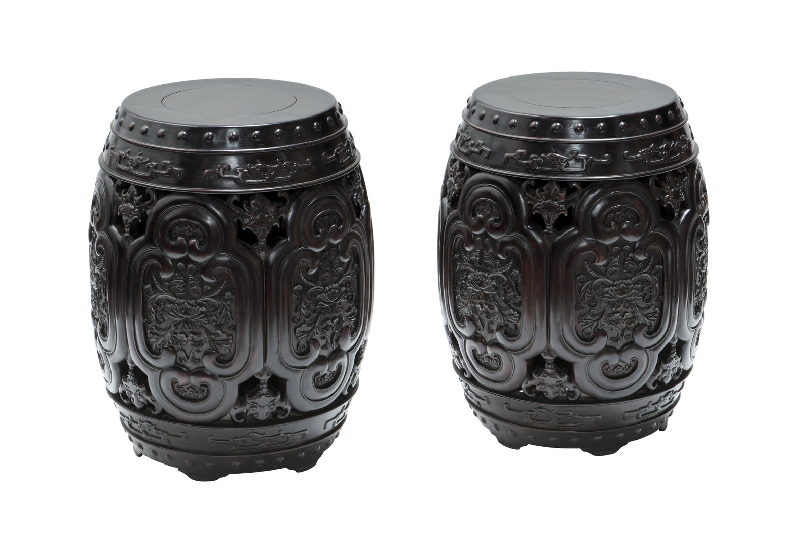 PAIR OF ROSEWOOD OR ZITAN BARREN-FORM STOOLS, QING: Each stool is formed of circular cross section above the rounded body, the seat is intricately carved with auspicious symbols of longevity bats, blossom peonies and ruyi-clouds form, with a row of rai