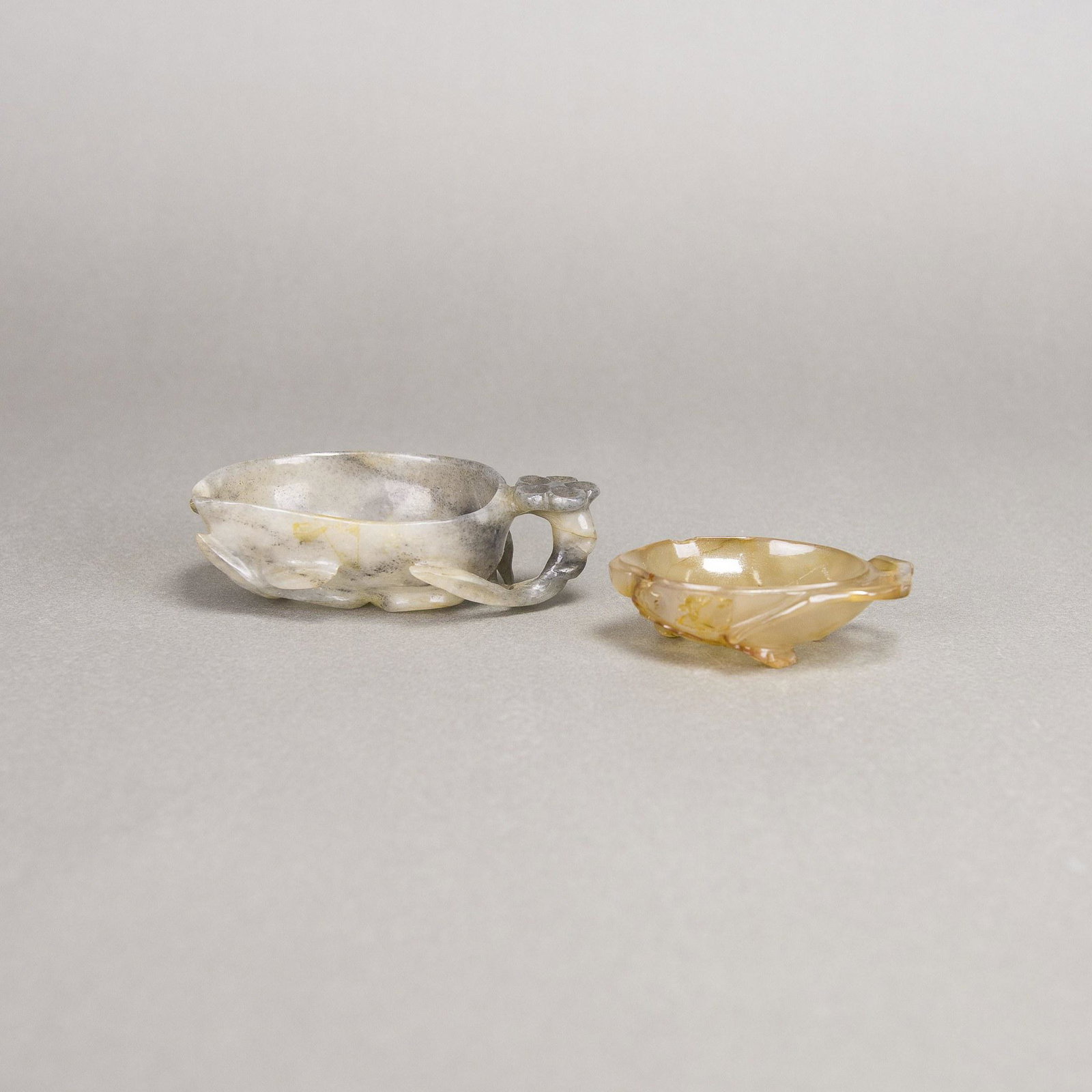 A PAIR OF CARVED LOTUS VINE AGATE BRUSH WASHERS: A pair of carved lotus vine agate brush washers, each carved in the form of a curled lotus leaf borne on a stem that is tied together with a branch with a lotus bud. 9.5x6x3cm 7x4.2x2cm