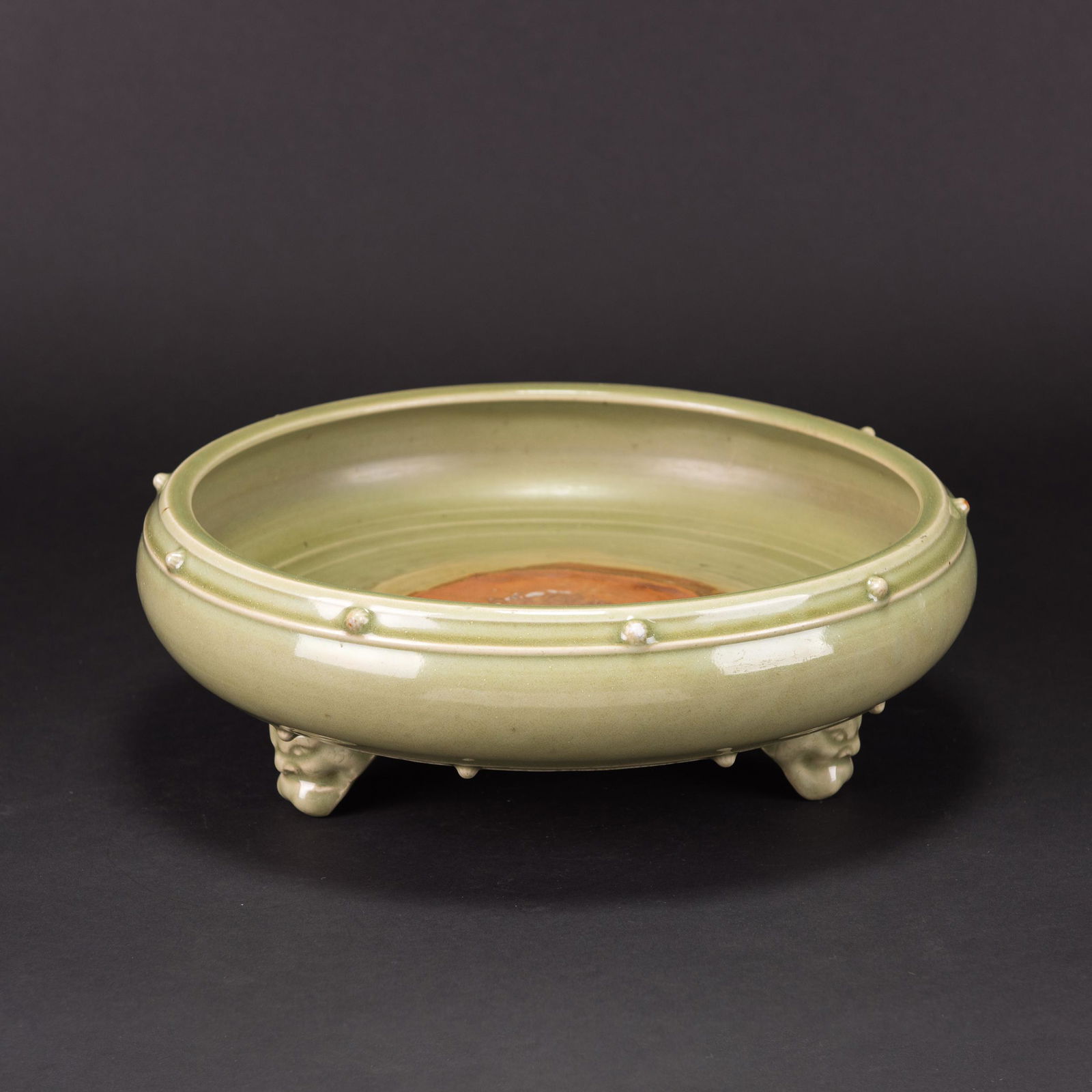 A LONGQUAN CELADON TRIPOD CENSER: A longquan celadon tripod censer, the compressed censer is supported on three animal-mask supports. The censer is covered overall with a glaze of yellowish-olive green tone. H11.5x32cm Condition: with