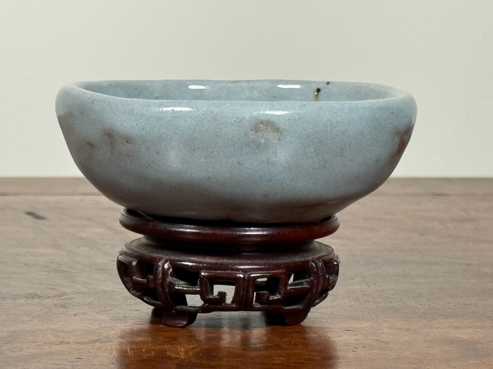 CHINESE GUAN GLAZED PORCELAIN CUP ON HARDWOOD BASE: Chinese Guan glazed porcelain cup on hardwood base. Cup has uneven glaze flaw. Dimensions: Diameter: 3.3 in. Note: This item is in New York, where it can be shipped from.