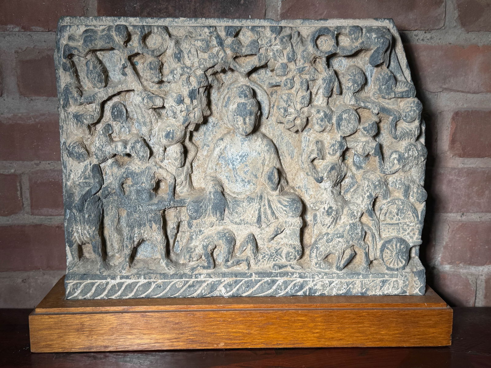 ANTIQUE GANDHARA STONE BUDDHA PLAQUE ON WOOD STAND: Anbtique gandhara stone carving on wood stand, stone without the base, heavy in weight. Dimensions: Width: 16 in. (40.6 cm); Height: 12 in. (30.5 cm) Note: This item is in New York, where it can be sh