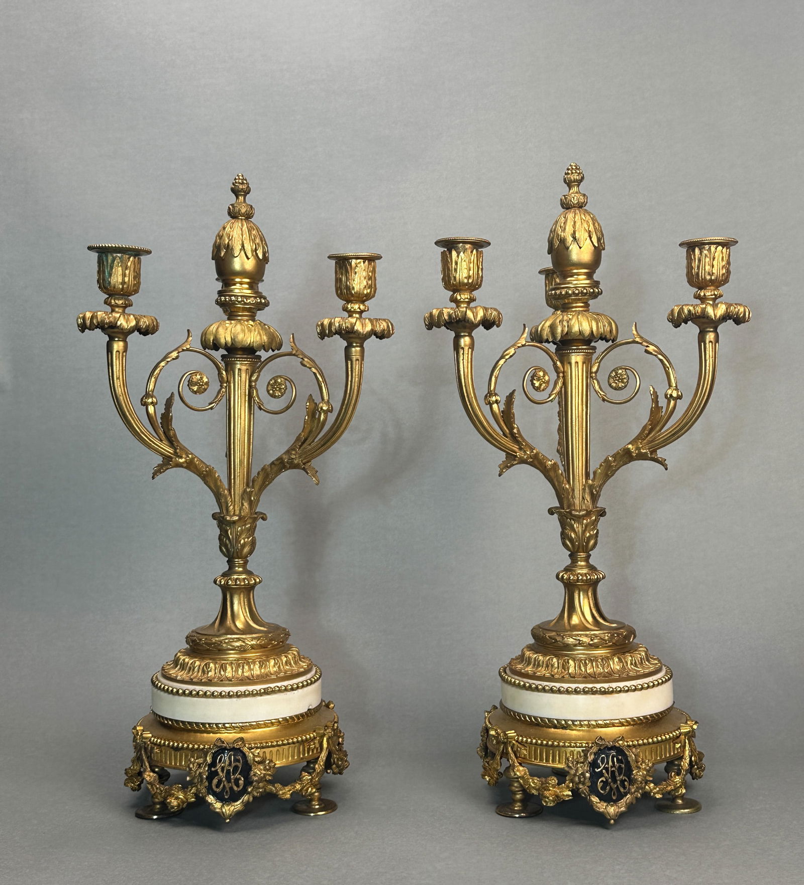 A PAIR OF ANTIQUE FRENCH GILT BRONZE CANDELABRA WITH FAMILY MONOGRAM: A pair of antique French gilt bronze and white marble candelabra with a family monogram, 19th century. Dimensions: Height: 19 in. (48.3 cm).