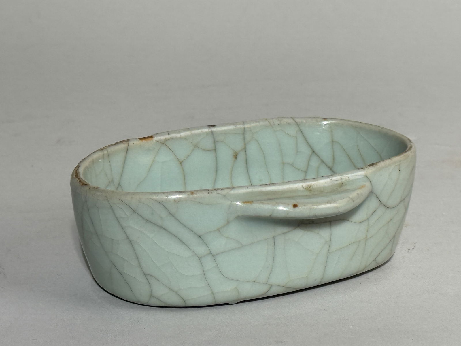 A CHINESE DOUBLE HANDLE EAR CUP WITH GUAN GLAZE: A Chinese double ear cup imitating a Han ritual bronze shape, with a Guan glaze, with glaze skipping on the rim. Dimensions: Length: 4.5 in. (11.4 cm).