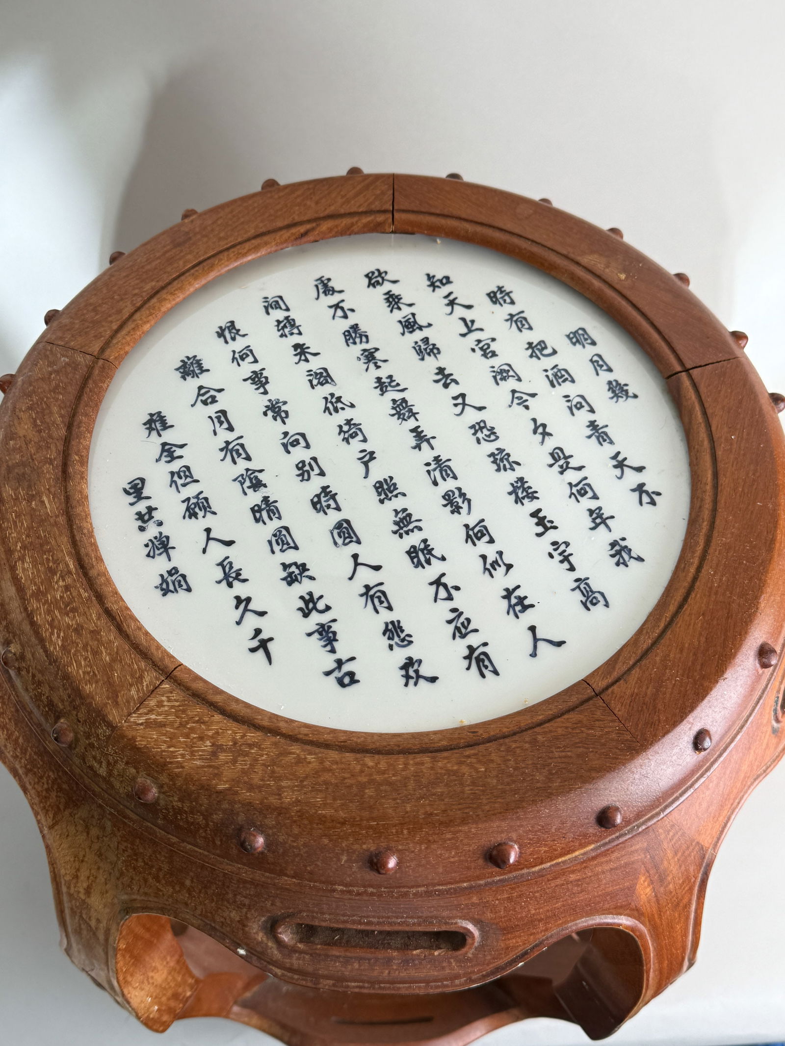 A CHINESE HARDWOOD STOOL WITH PORCELAIN TILE: A Chinese hardwood stool with a porcelain tile, painted calligraphy on top. Dimensions: Height: 18 in. (45.7 cm); Diameter: 15 in. (38.1 cm).