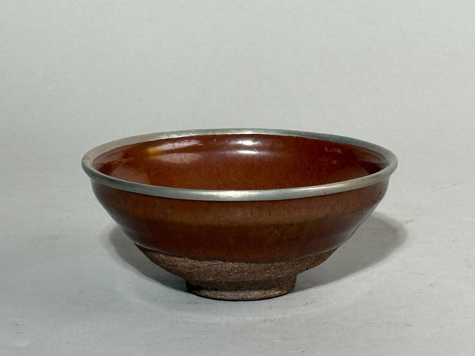 A CHINESE BROWN GLAZED TEA BOWL WITH METAL RIM: A Chinese brown glazed tea bowl with a metal rim. Dimensions: Diameter: 4.2 in. (10.7 cm).